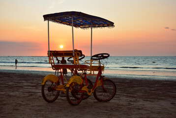two persons bicycle on Chaung Thar beach during Sunset