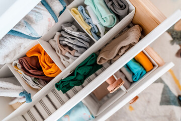 Baby's clothes neatly laid out in the chest of drawers. Organization of the children's closet. Motherhood, cleaning home kids wardrobe.