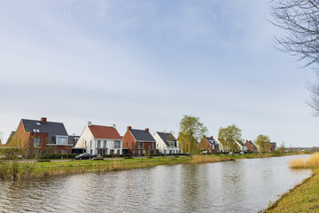 Fototapeta na wymiar Row of modern newly build family houses along canal in Kortenoord in Wageningen, Gelderland in The Netherlands