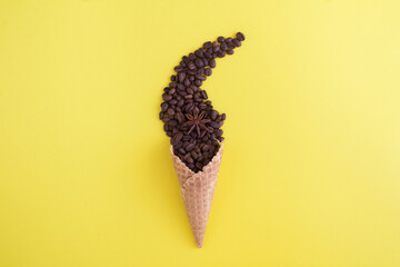 Ice cream cone with coffee beans on the yellow background. Closeup.