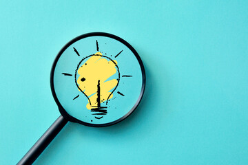 A burning light bulb under a magnifying glass. Search for a creative idea