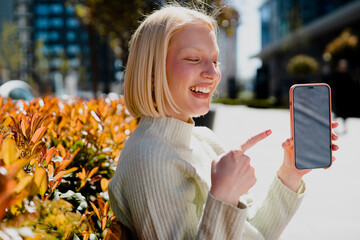 Happy young girl sitting in the park listening the music. Beautiful woman having video call