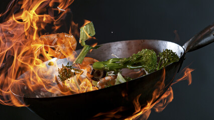 Freeze Motion of Wok Pan with Flying Ingredients in the Air and Fire Flames.