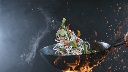 Freeze Motion of Wok Pan with Flying Ingredients in the Air and Fire Flames.