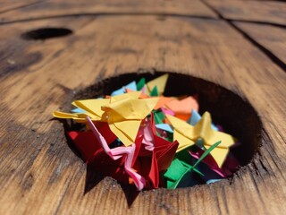 Origami colorati a forma di farfalle, ammucchiate in un buco in un tavolone di legno