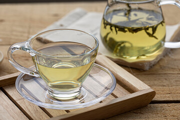 glass cup of green tea and teapot isolated on wooden background.