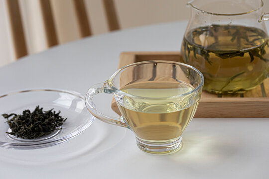 glass cup of green tea and teapot isolated on wooden background.
