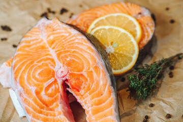 Slices of fresh salmon with lemon, black pepper and herbs on paper.