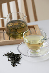 glass cup of green tea and teapot isolated on wooden background.