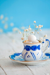 Tacita vintage rellena de huevos de pascua y pequeñas flores alrededor