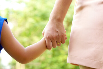 Mother's hand holding a little girl's hand on bokeh background. Love and family concept.