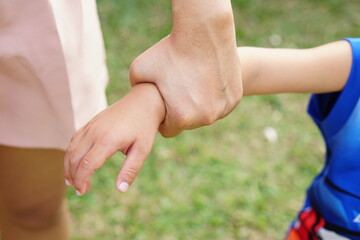 Mother's hand holding a little girl's hand on bokeh background. Love and family concept.