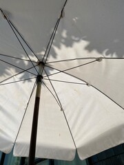 High angle view of white umbrella with tree shadow in the background, concept about resort and relax.