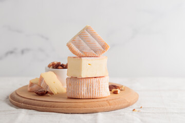 Sliced soft cheese with mold on a wooden board on a white background