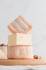 Sliced soft cheese with mold on a wooden board on a white background