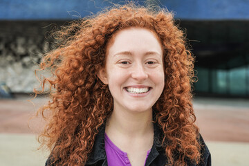 Happy redhead girl smiling on camera in the city