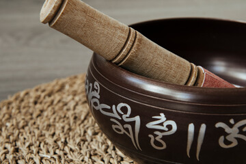 metal meditation bowl with a wooden stick on an esparto grass table cloth