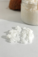 Scattered scrub, jar, coconut on white background. Home spa treatment concept, organic cosmetic. Vertical photo
