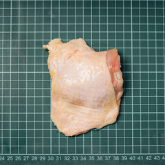 Raw chicken thigh with skin, boneless, for cooking on wooden cutting board.Chicken thigh meat on a...