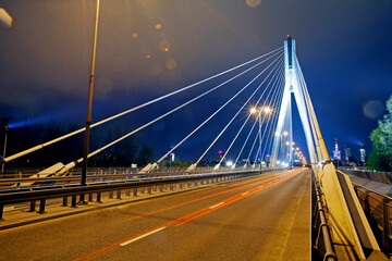 Long exposure shot of Swietokrzyski Bridge spanning the Vistula River illuminated at night