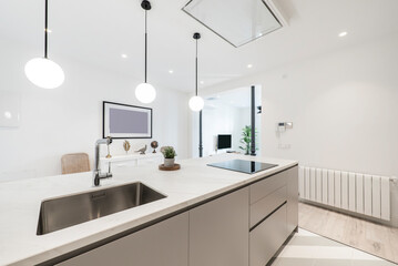 Kitchen island with built-in stainless steel sink with chrome tap, black ceramic hob and extractor hood, white aluminum radiator and lamps with spherical tulips
