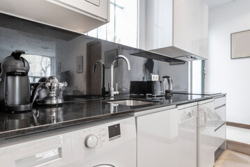 Fototapeta premium kitchen with black marble countertop with small appliances and washing machine