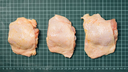 Raw chicken thigh with skin, boneless, for cooking on wooden cutting board.Chicken thigh meat on a...