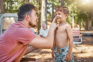 Dont forget your sunscreen. Cropped shot of a handsome young man putting sunblock on his adorable little son while camping in the woods. - Powered by Adobe