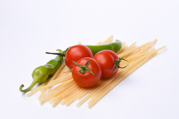 Green peppers, red tomatoes and pasta isolated on white background.