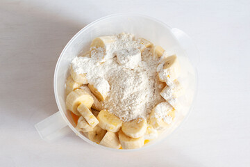 Ingredients for cottage cheese casserole in a mixing bowl. Cottage cheese, bananas, flour, eggs, honey
