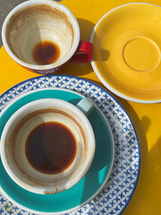 Dirty multi-colored cup after coffee, tea, cocoa. Yellow table, red cup