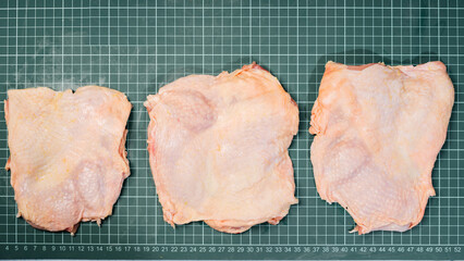 Chicken thigh meat on a linear board. Raw chicken thigh with skin, boneless, for cooking.