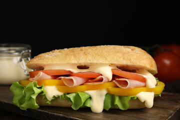 Delicious sandwich with vegetables, ham and mayonnaise on wooden table, closeup