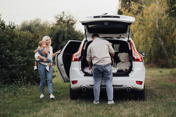 Two Parents with Their Little Kid Preparing to Picnic Time Outdoors, Young Family Enjoying Road Trip on the SUV Car