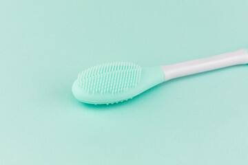 Silicone brush for cleansing and scrubbing the face from cosmetics. Turquoise color close-up. Turquoise background.