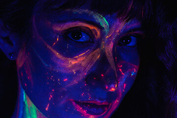 close-up of a girl's face made up with coloured fluorescent paint on her face
