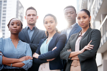 Fototapeta premium We strive for corporate excellence. Shot of a group of young businesspeople standing with their arms crossed against a city background.