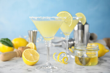 Delicious bee's knees cocktails and ingredients on white marble table against light blue background