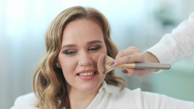 Pretty woman applying makeup in beauty salon.