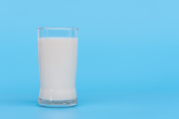 World Milk Day, A glass of white milk isolated on a blue background, close up. Happy Milk Day. Dairy product concept, copy space on right for design or content, nobody, World Milk Day 1 June