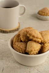 Сottage layer cookies with sugar and cinnamon in the white ceramic bowl, mug with black coffee