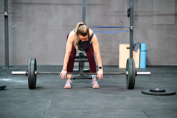 Fototapeta na wymiar Young fitness woman training at the gym. Lifting weights in squat position