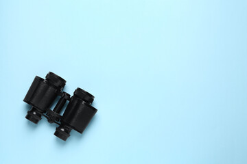 Modern binoculars on light blue background, top view. Space for text