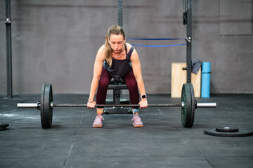 Fototapeta na wymiar Young fitness woman training at the gym. Lifting weights in squat position