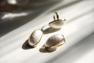Golden white earrings and a ring in sunny rays