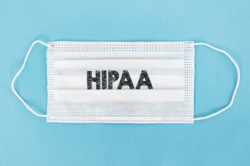 Word HIPAA Health Insurance Portability and Accountability Act printed on a white medical mask over blue background. - obrazy, fototapety, plakaty