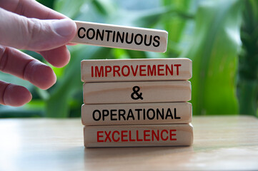 Hand holding wooden blocks with text - Continuous improvement and operational excellence. - obrazy, fototapety, plakaty