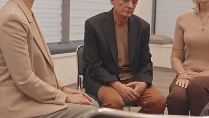 Medium slowmo of senior Caucasian man sharing his destructive feelings and emotions to people at support group, seeking for support