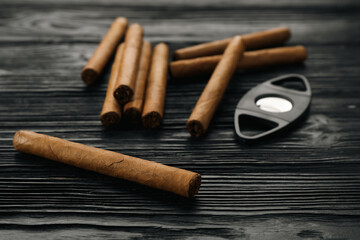 Cigars and guillotine cutter on black wooden table