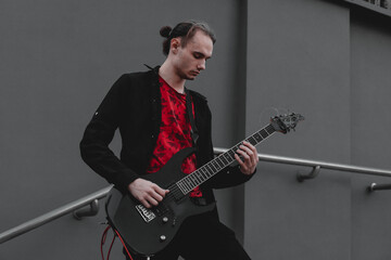 A male musician with an electric guitar on a gray background, in front